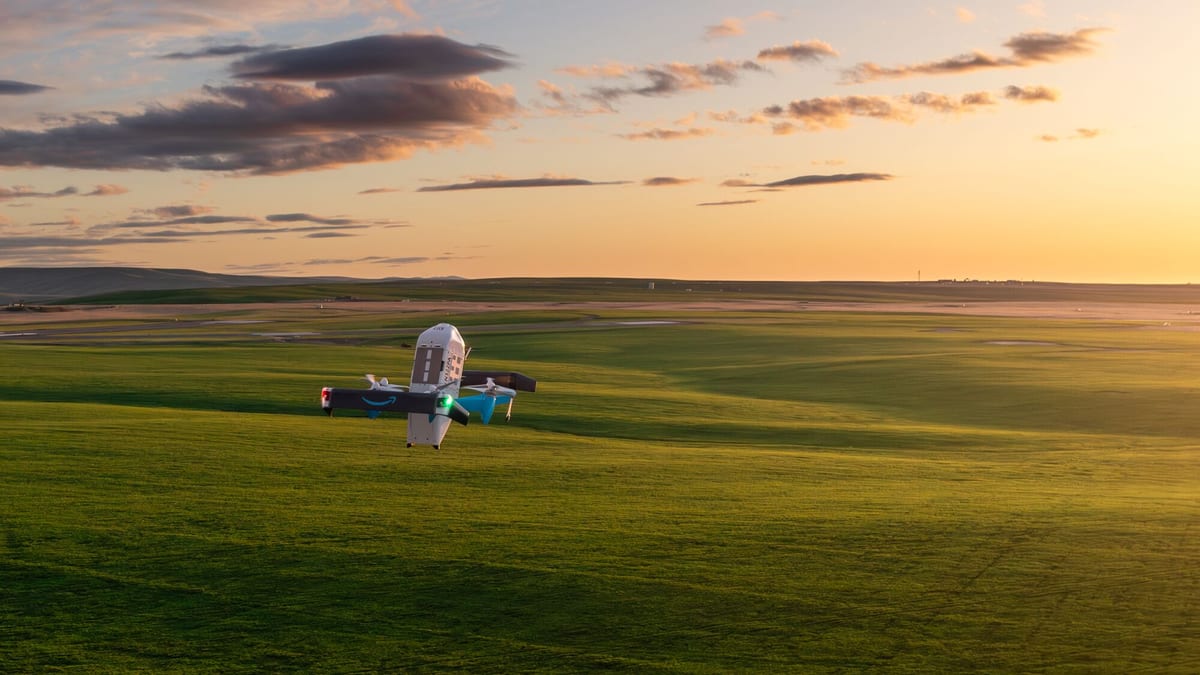 An Amazon Prime Air MK30 delivery drone flying over grassland at sunset