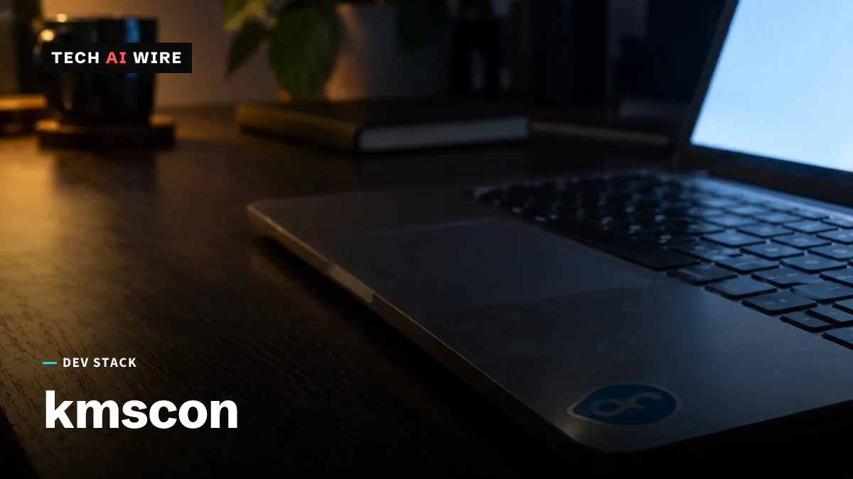 An open laptop on a desk in a dim room, its screen glowing across the keyboard, with a Fedora logo sticker on the palm rest.