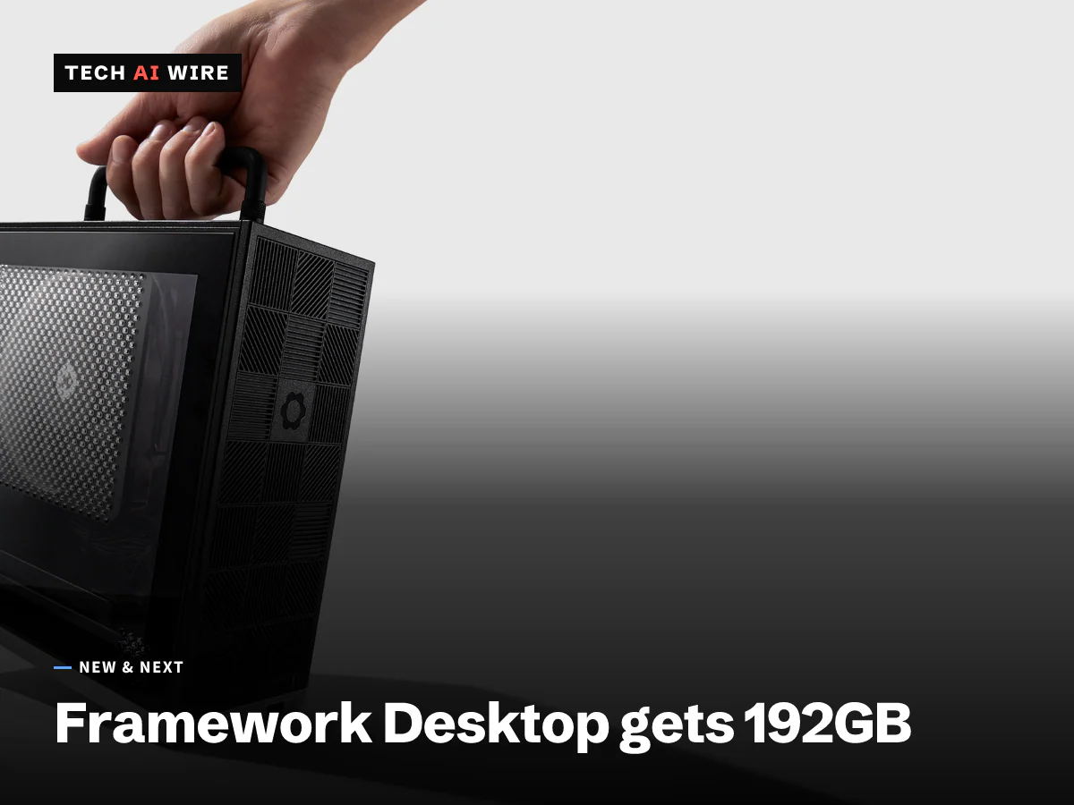 A hand lifting a small black Framework Desktop by its top handle, showing the perforated side panel and the patterned front with the Framework gear logo, against a light gray backdrop.