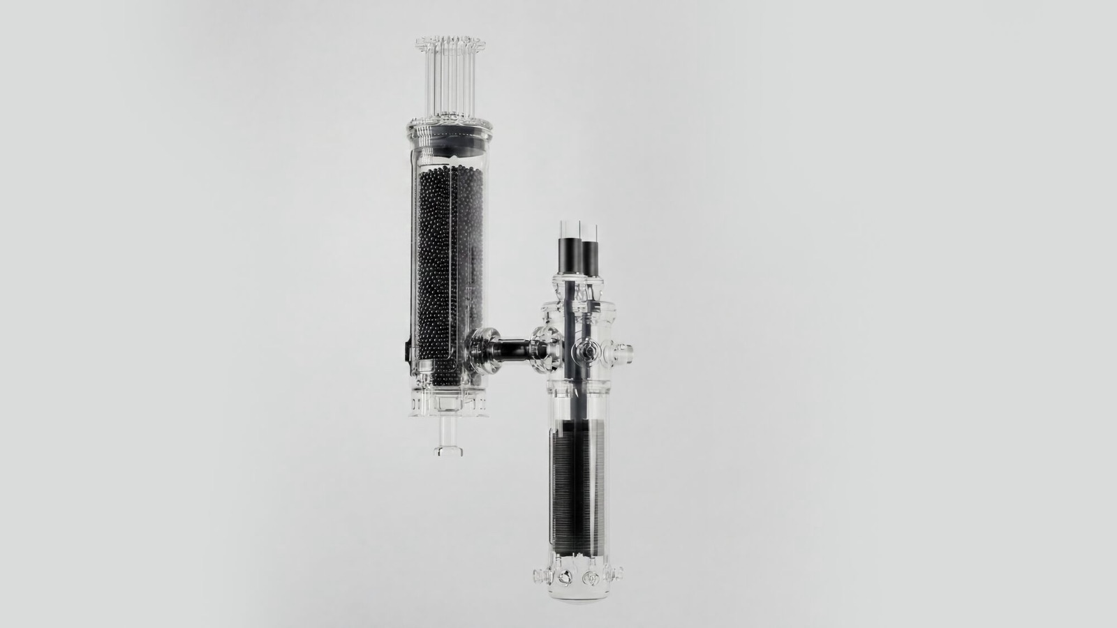 X-energy's Xe-100 reactor shown as a clear cutaway model, its tall vessel filled with dark fuel pebbles beside a second connected vessel.