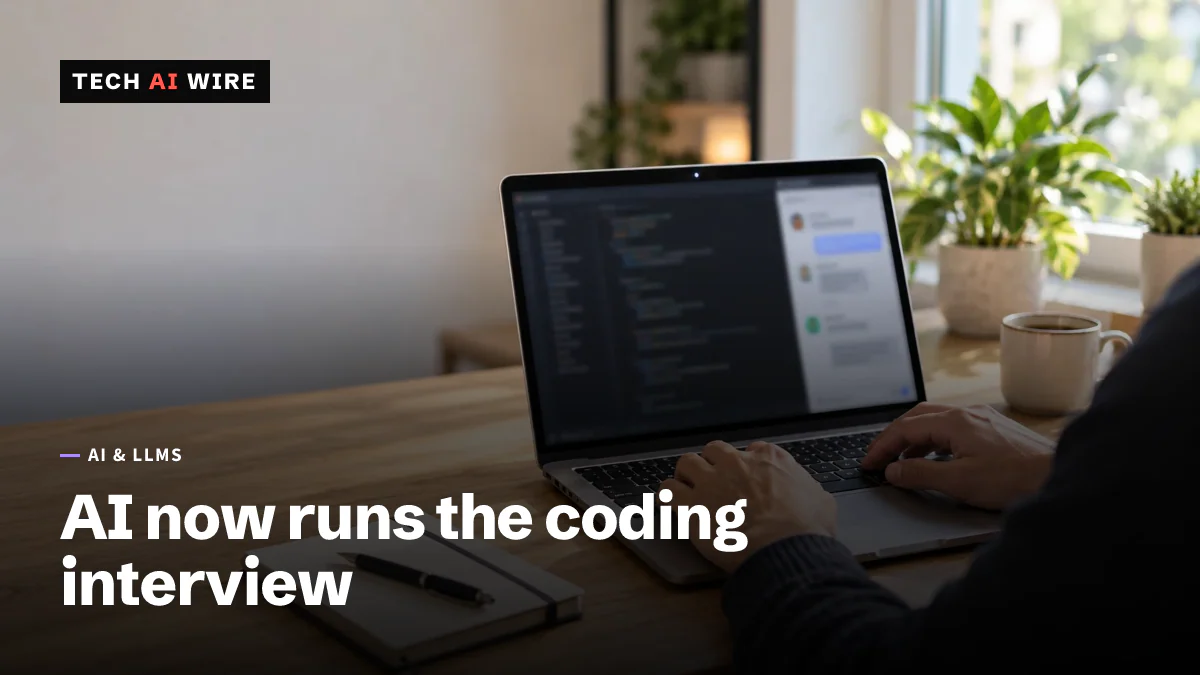 A developer types on a laptop showing a code editor and a chat panel during a remote coding interview, with a notebook and a coffee mug on a wooden desk.
